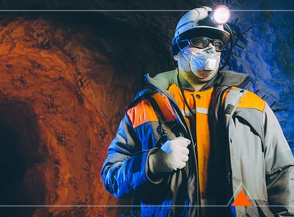 Minero con casco, lámpara y equipo de protección en el interior de una mina